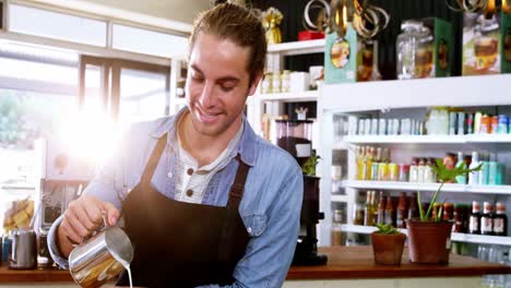 Smiling-waiter-making-cup-of-coffee-at-counter