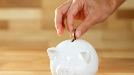 Woman-putting-coin-in-piggy-bank