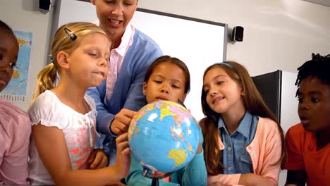 Teacher-discussing-over-a-globe-with-kids-in-classroom