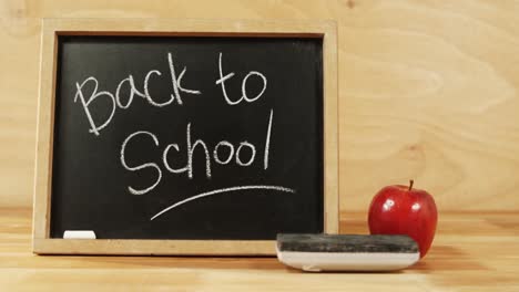 Close-up-of-chalkboard-with-blackboard-duster-and-apple