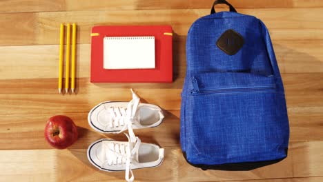 Close-up-of-school-bag-with-shoes-and-apple