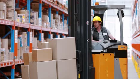 Male-warehouse-worker-using-forklift-truck-for-lifting-stock
