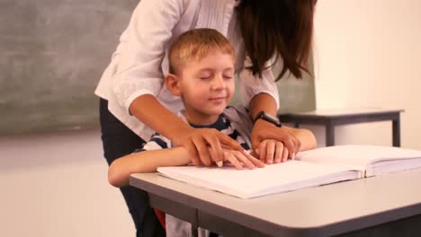 Teacher-helping-a-blind-schoolboy-with-his-homework-in-classroom