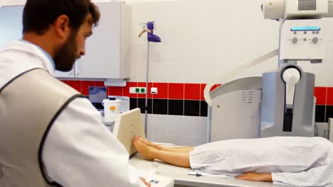 El-Médico-Masculino-Configura-La-Máquina-Para-Realizar-Una-Radiografía-A-Una-Paciente