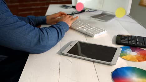 Männlicher-Grafikdesigner,-Der-Ein-Digitales-Tablet-Verwendet,-Während-Er-Am-Computer-Arbeitet