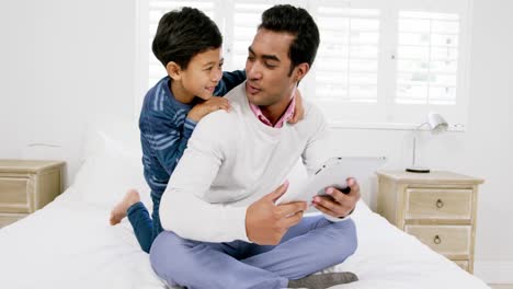 Vater-Und-Sohn-Nutzen-Digitales-Tablet-Auf-Dem-Bett