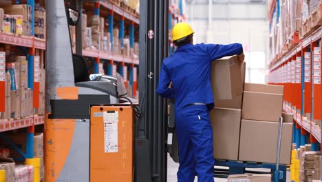 Male-warehouse-worker-arranging-stock-on-forklift-truck