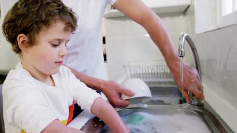 Son-helping-father-in-washing-utensils