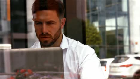 Businessman-having-a-cup-od-coffee-while-using-laptop