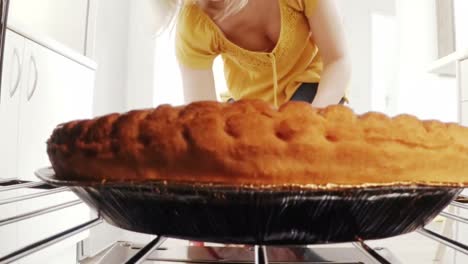 Woman-removing-a-baking-pan-with-sweet-food-from-oven