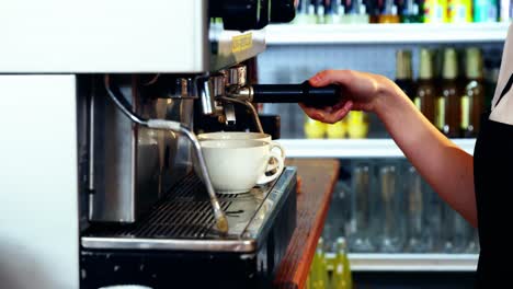 Waitress-making-cup-of-coffee-at-counter-in-kitchen