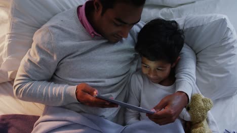 Vater-Und-Sohn-Nutzen-Digitales-Tablet-Auf-Dem-Bett