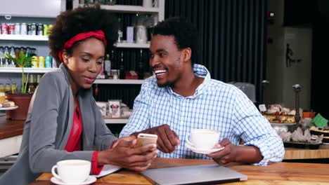 Man-and-woman-interacting-with-each-other-while-having-cup-of-coffee