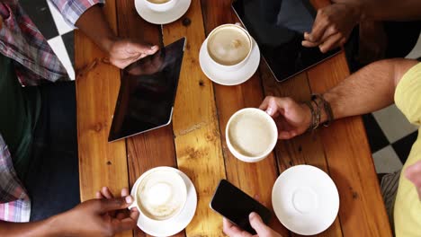 Gruppe-Von-Freunden,-Die-Mobiltelefon-Und-Digitales-Tablet-Nutzen,-Während-Sie-Eine-Tasse-Kaffee-Trinken