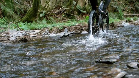 Mountain-biker-riding-bicycle-in-creek
