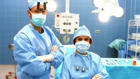 Porträt-Männlicher-Und-Weiblicher-Chirurgen-Mit-Verschränkten-Armen-Im-Operationssaal