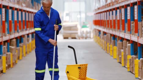 Male-warehouse-worker-moping-floor