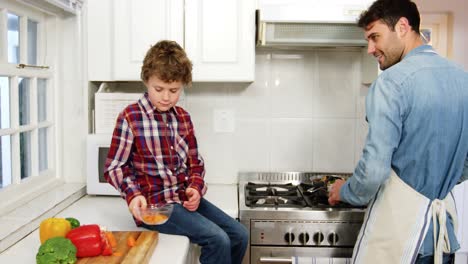 Niño-Ayudando-A-Padre-Mientras-Cocina-Comida-En-La-Cocina