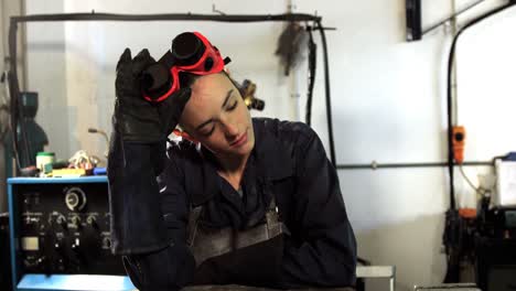 Female-welder-leaning-in-workshop