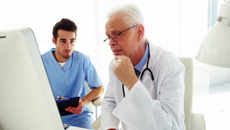 Male-doctor-and-coworker-discussing-over-computer