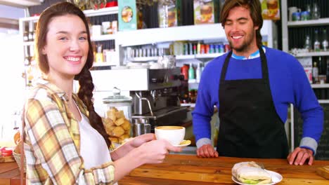 Waiter-serving-a-cup-of-coffee-to-customer-at-counter