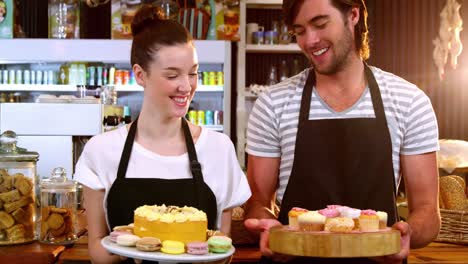 Portrait-of-waiter-and-waitress-holding-a-tray-of-cupcakes