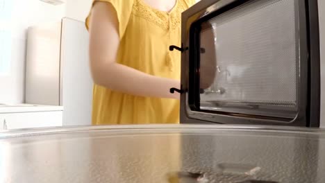 Woman-putting-a-baking-pan-with-sweet-food-to-bake-in-oven