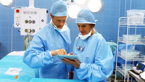 Männliche-Und-Weibliche-Chirurgen-Nutzen-Ein-Digitales-Tablet-Im-Operationssaal