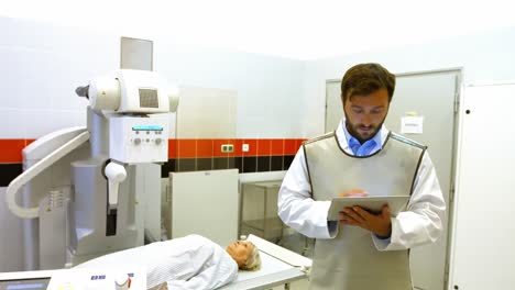 Médico-Varón-Usando-Tableta-Digital-En-La-Sala-De-Rayos-X