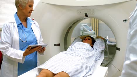 Doctor-reviewing-chart-of-female-patient-on-digital-tablet-before-mri-scan
