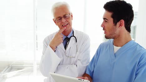 Male-doctor-and-coworker-discussing-over-digital-tablet