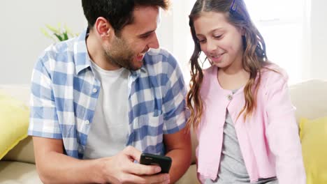 Father-and-daughter-using-mobile-phone-in-the-living-room