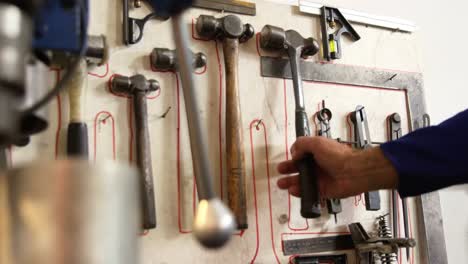 Welder-taking-hammer-from-tool-rack