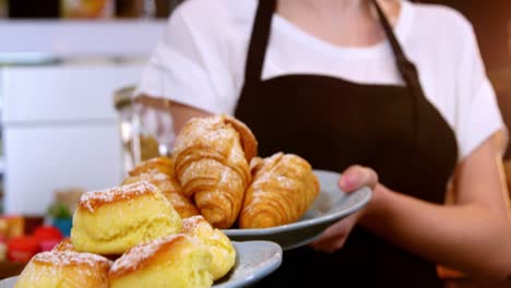 Waitress-holding-a-plate-of-croissant-and-sweet-food
