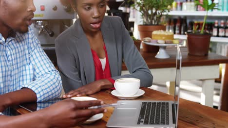 Man-and-woman-using-a-laptop-while-having-cup-of-coffee