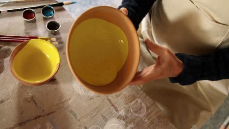 Male-potter-mixing-watercolor-in-bowl-at-pottery-workshop