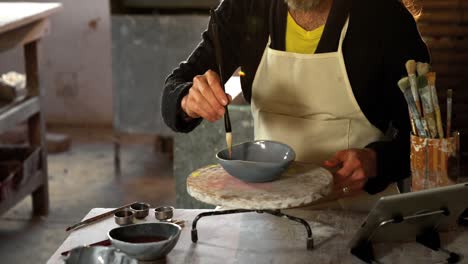 Attentive-male-potter-painting-on-bowl