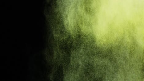Green-and-yellow-dust-powder-blowing-against-black-background