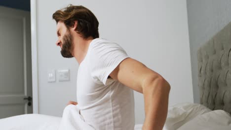Young-man-waking-up-in-bed-and-stretching-his-arms