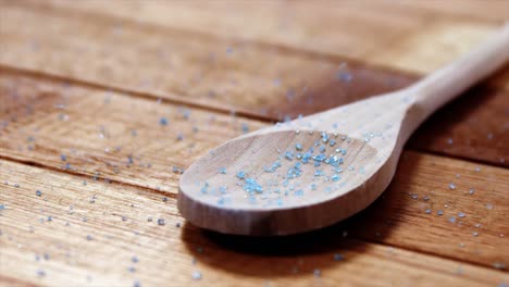Crystals-of-blue-frit-glass-falling-wooden-spoon