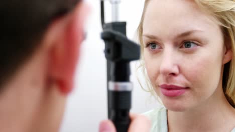 Optometrista-Examinando-A-Una-Paciente-A-Través-Del-Oftalmoscopio