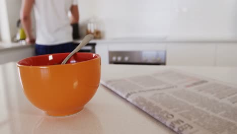 Close-up-of-breakfast-bowl-with-newspaper-in-kitchen