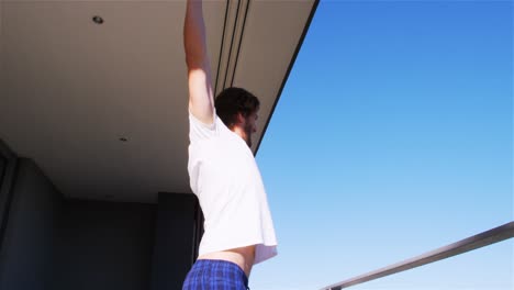 Man-stretching-his-arms-in-balcony