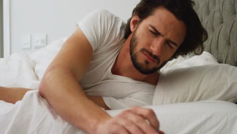 Man-turns-off-alarm-on-his-mobile-phone-in-bedroom