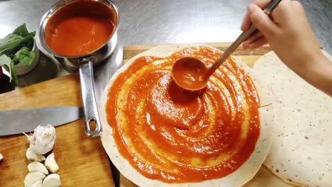 Hand-of-chef-preparing-pizza