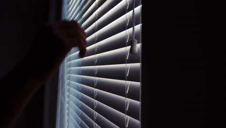 Man-looking-through-window-blinds-after-waking-up