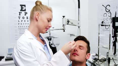 Female-optometrist-putting-eye-drop-in-patient-eyes