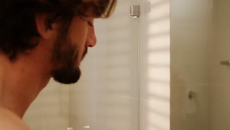 Man-washing-his-face-in-bathroom