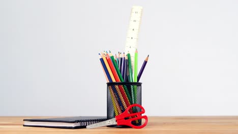 Close-up-of-pen-holder-with-colored-pencil,-diary-and-scissors