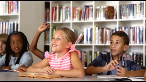 School-kids-raising-hand-in-library